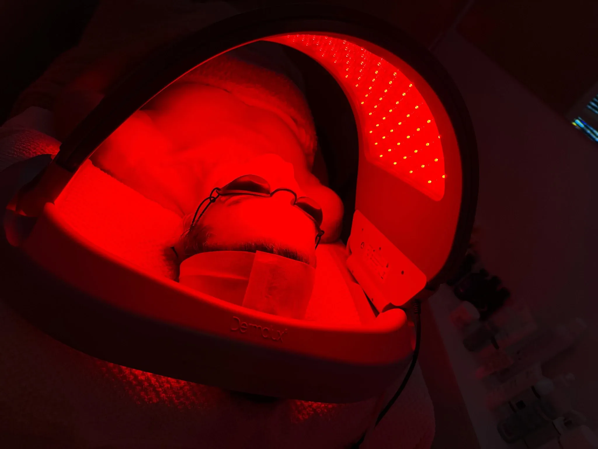 Client relaxing beneath an LED light therapy device at The Beautician in Newcastle.